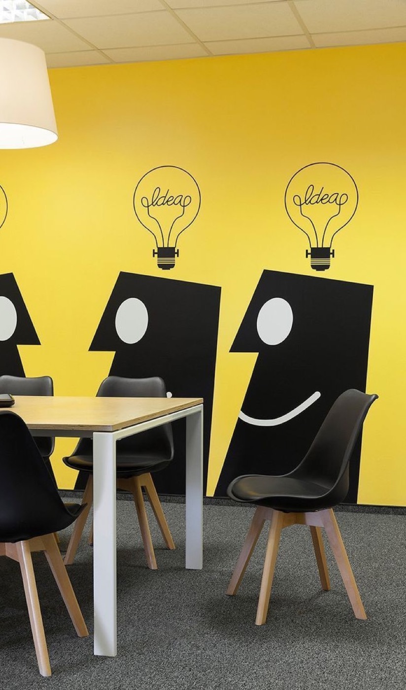 Bright yellow office mural with playful idea-character illustrations